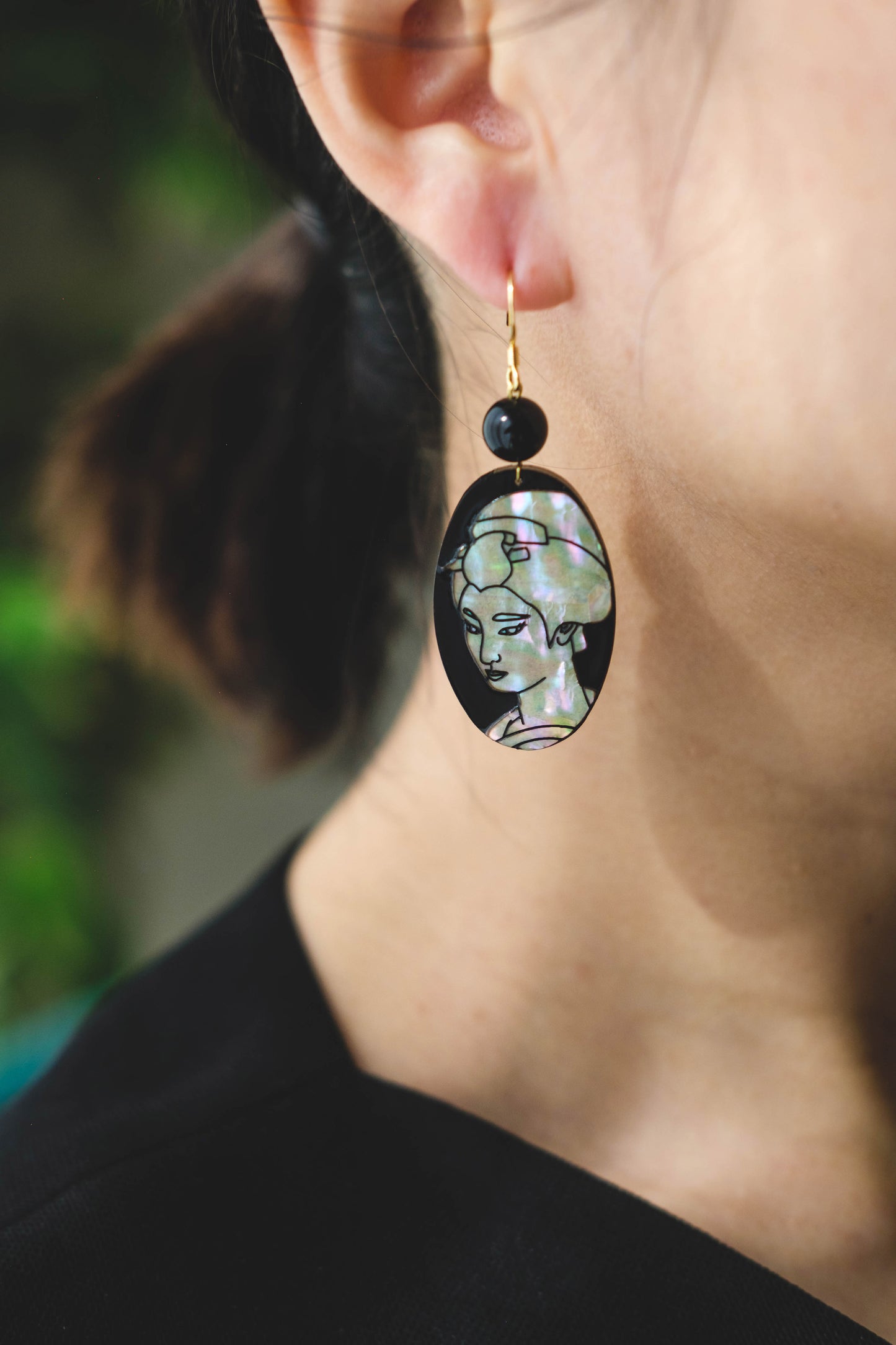 Mother of pearl earrings with engraved cherry blossms and portrait of a woman.